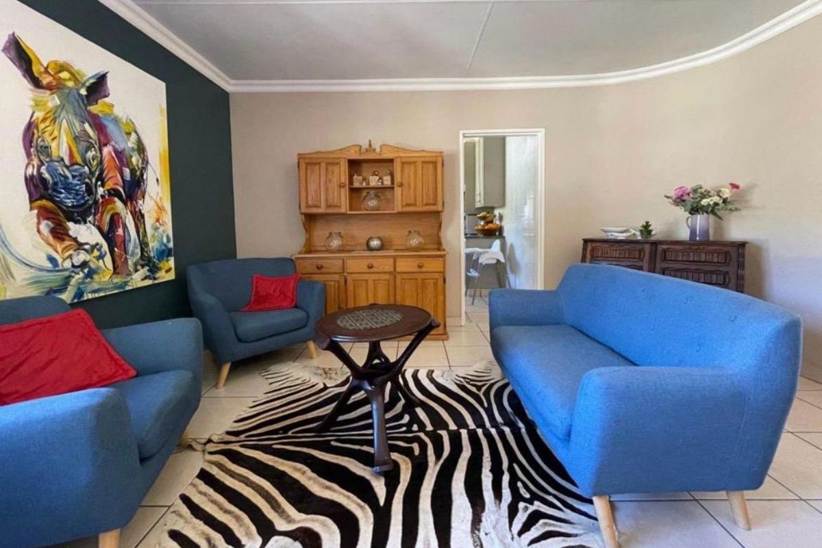 A comfortable living room featuring tiled flooring, coved ceilings, and a dark accent wall, with an open doorway leading to the kitchen area.