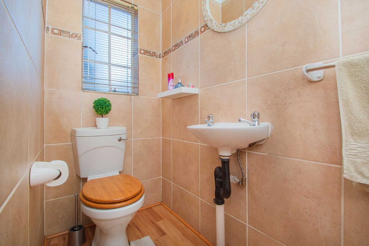 A compact guest bathroom featuring floor-to-ceiling ceramic wall tiles, a pedestal basin, and a standard toilet.