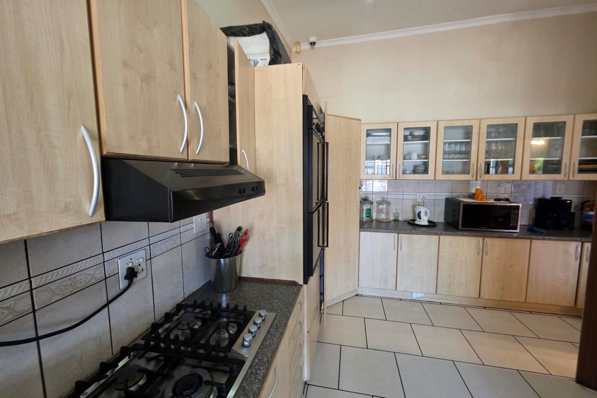 A functional kitchen featuring light wood cabinetry, a gas hob, built-in oven, and tiled flooring with ample counter space.