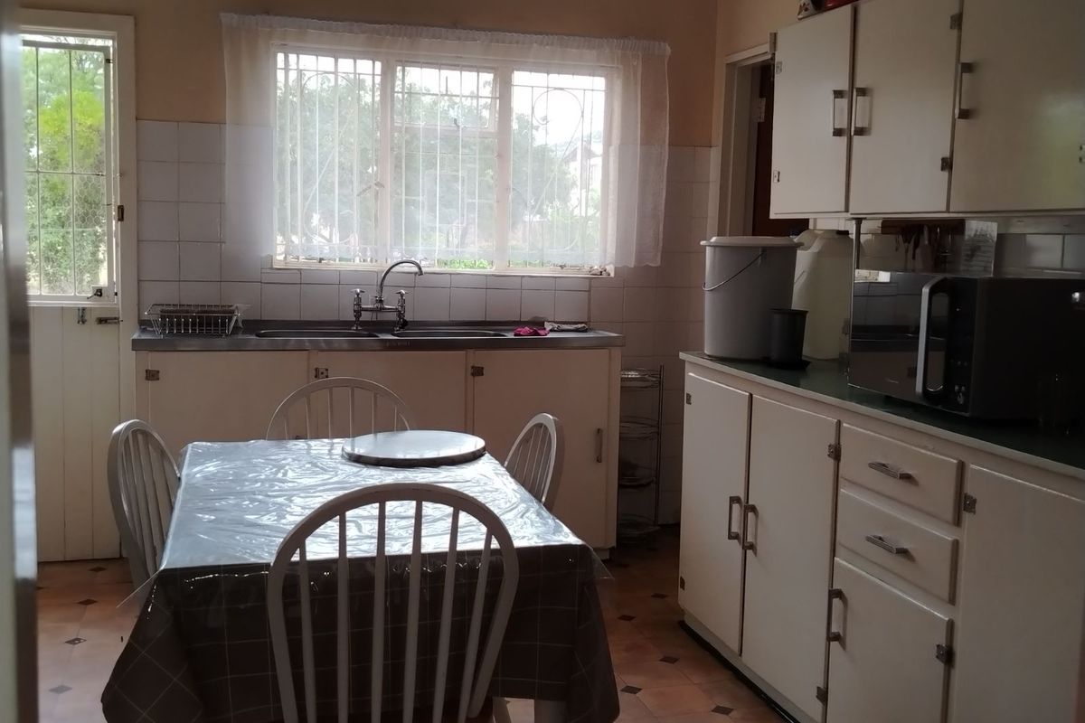 A dated kitchen featuring original cabinetry, tiled splashbacks, and a functional layout with a dedicated dining area.