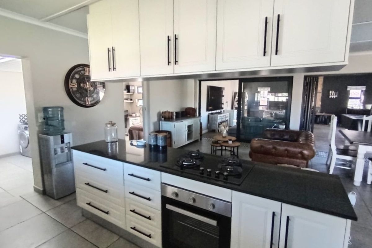 Modern kitchen featuring a central island with a built-in gas hob and oven, complemented by white cabinetry and dark stone countertops.