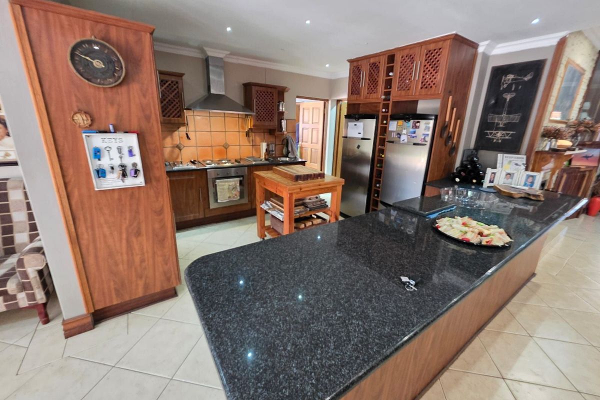 Spacious kitchen featuring dark wood cabinetry, granite countertops, a large central island, and integrated stainless steel appliances.