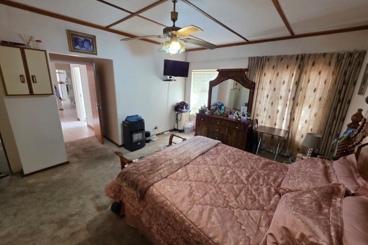 Spacious bedroom featuring carpeted flooring, a ceiling fan, and built-in storage, offering a functional layout with direct access to the hallway.