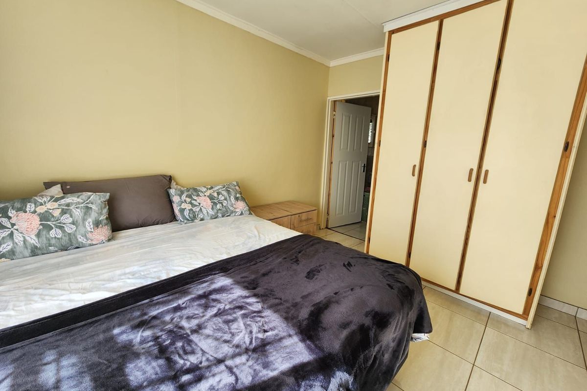 A bedroom featuring built-in wooden cupboards and tiled flooring, providing functional storage space within the townhouse.