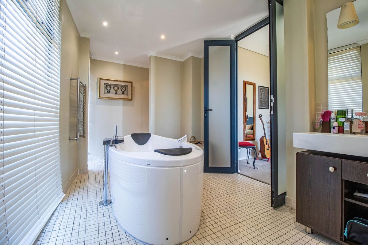 Modern bathroom featuring a freestanding oval bathtub, wall-mounted heated towel rail, and a vanity unit with a basin.