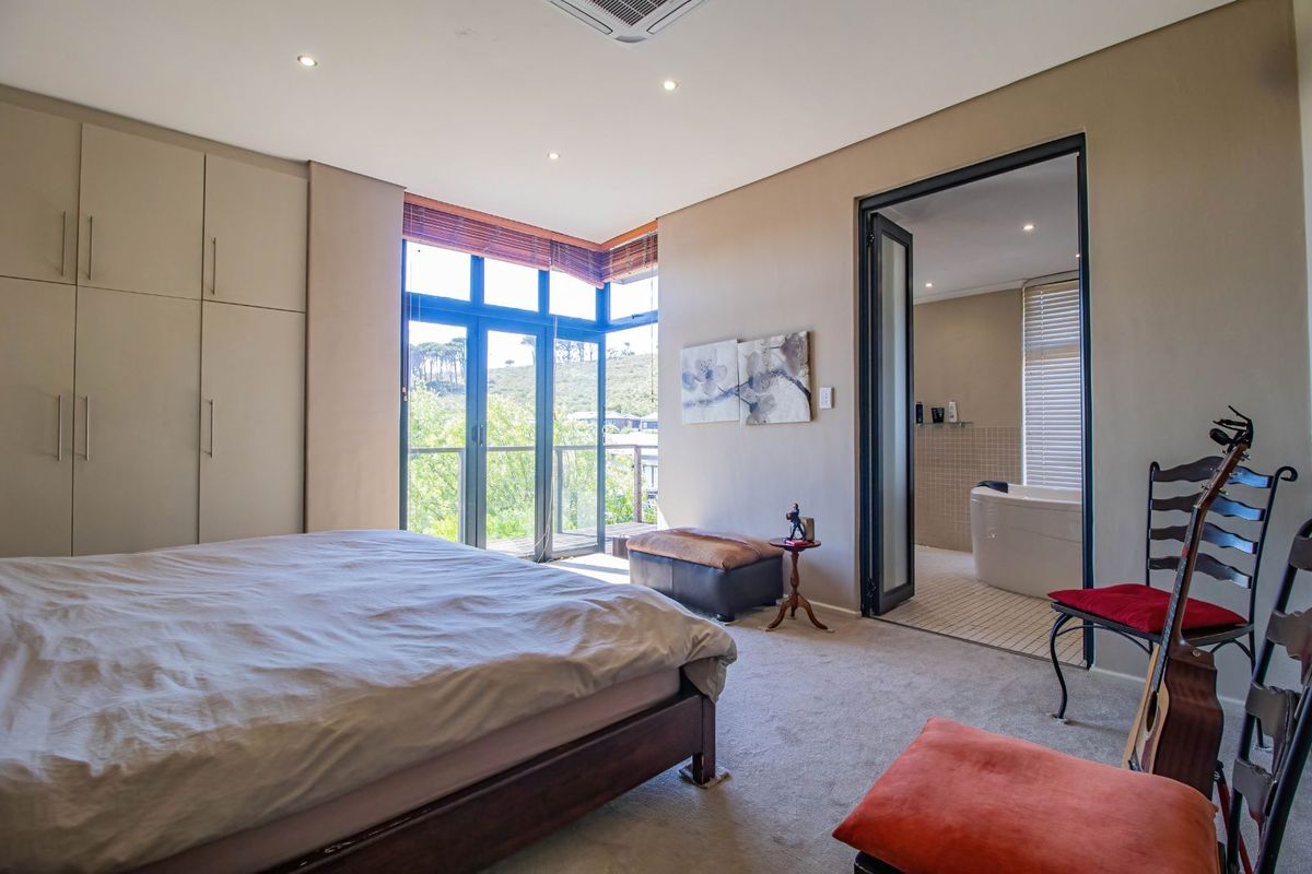 Spacious bedroom featuring built-in cupboards, carpeted flooring, and direct access to an en-suite bathroom and a private balcony with scenic views.