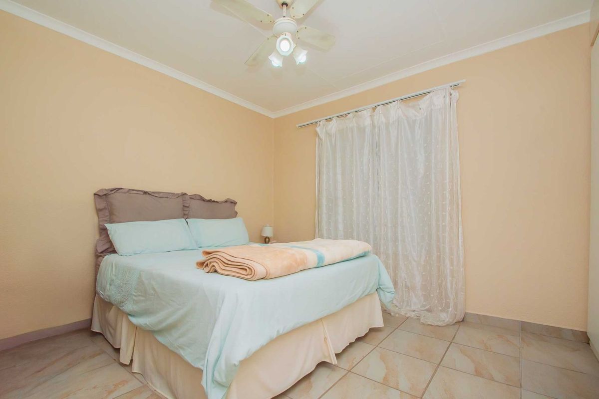 A bedroom featuring tiled flooring, a ceiling fan with integrated lighting, and a window with curtain tracks.