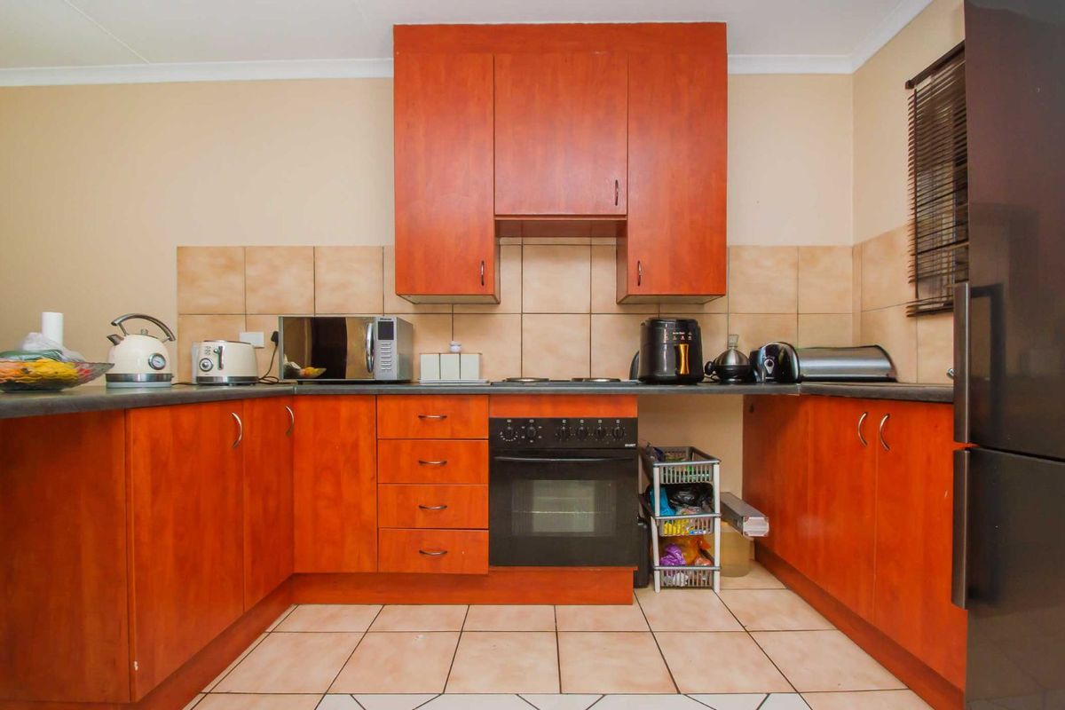 A functional kitchen featuring wood-finish cabinetry, tiled splashbacks, a built-in oven, and a hob, providing a practical workspace for daily cooking.