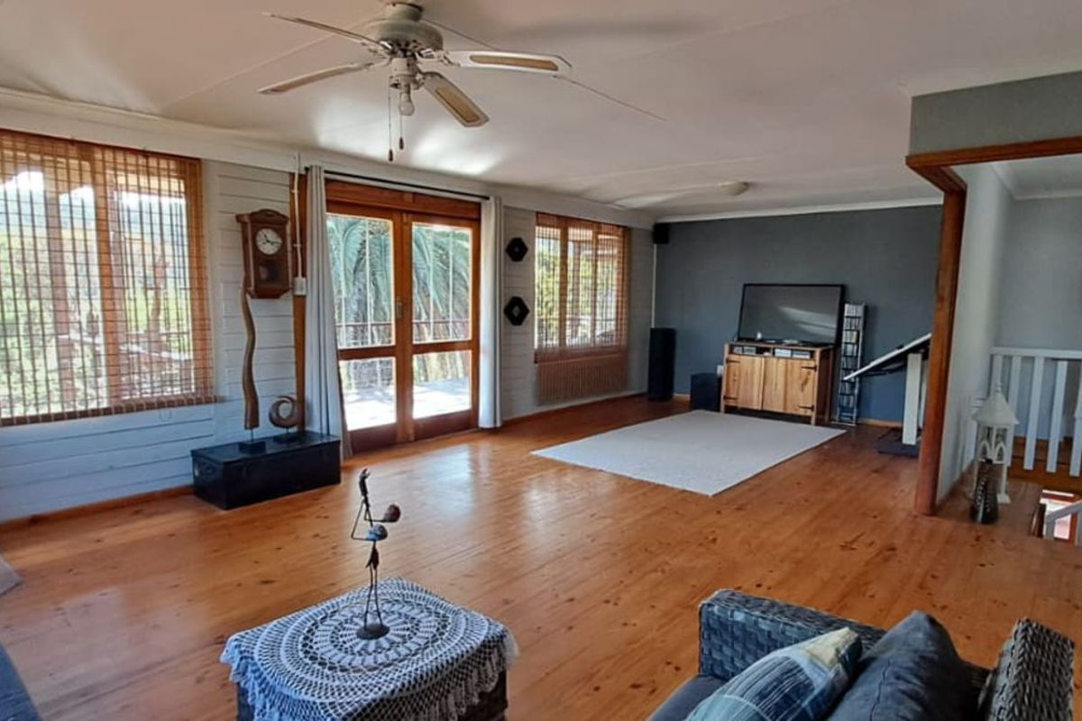 Spacious living area featuring polished timber flooring, a built-in wood-burning fireplace, ceiling fan, and direct access to an outdoor balcony.