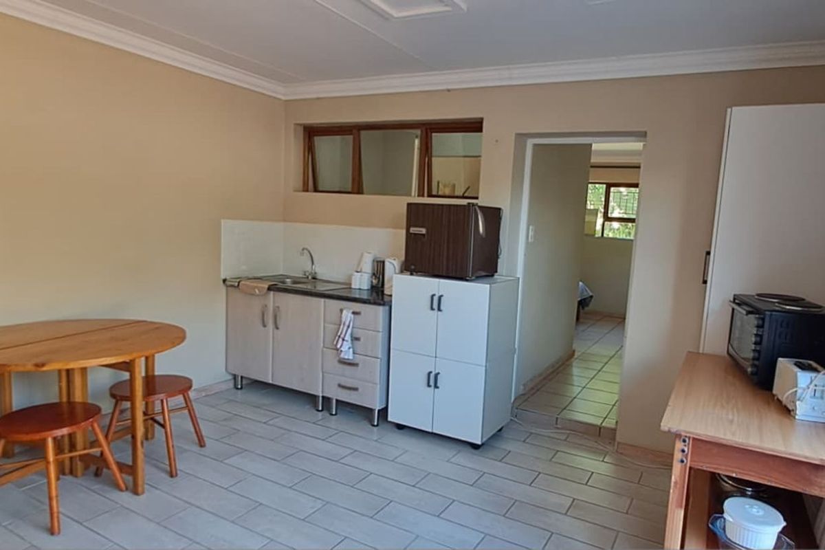 A compact kitchenette area featuring basic cabinetry, a sink, and tiled flooring, with an adjacent doorway leading to another room.