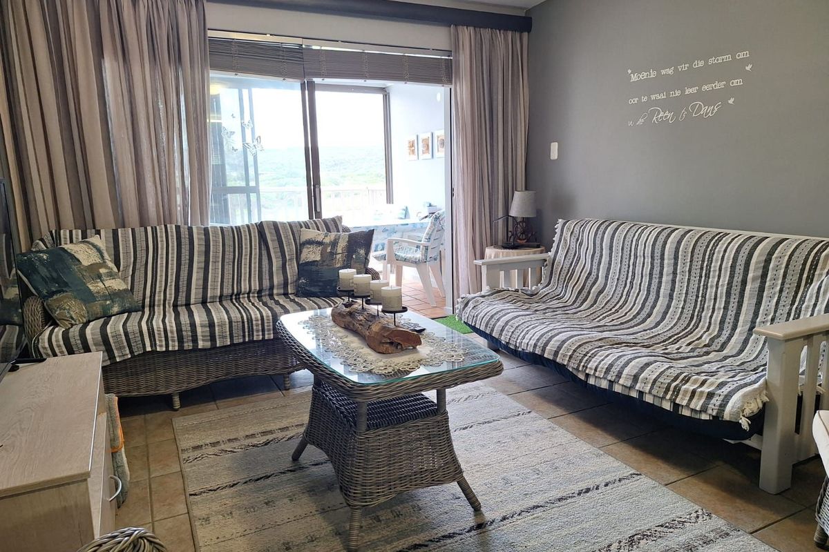 A comfortable living room featuring tiled flooring and large sliding glass doors that provide access to an adjoining patio area.