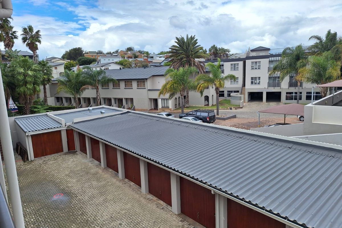 Elevated view overlooking a complex of residential apartment buildings with a row of garages and paved driveway area.
