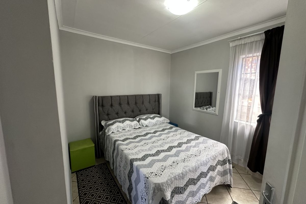 A functional bedroom featuring tiled flooring, a window with curtain treatments, and a central ceiling light fixture.