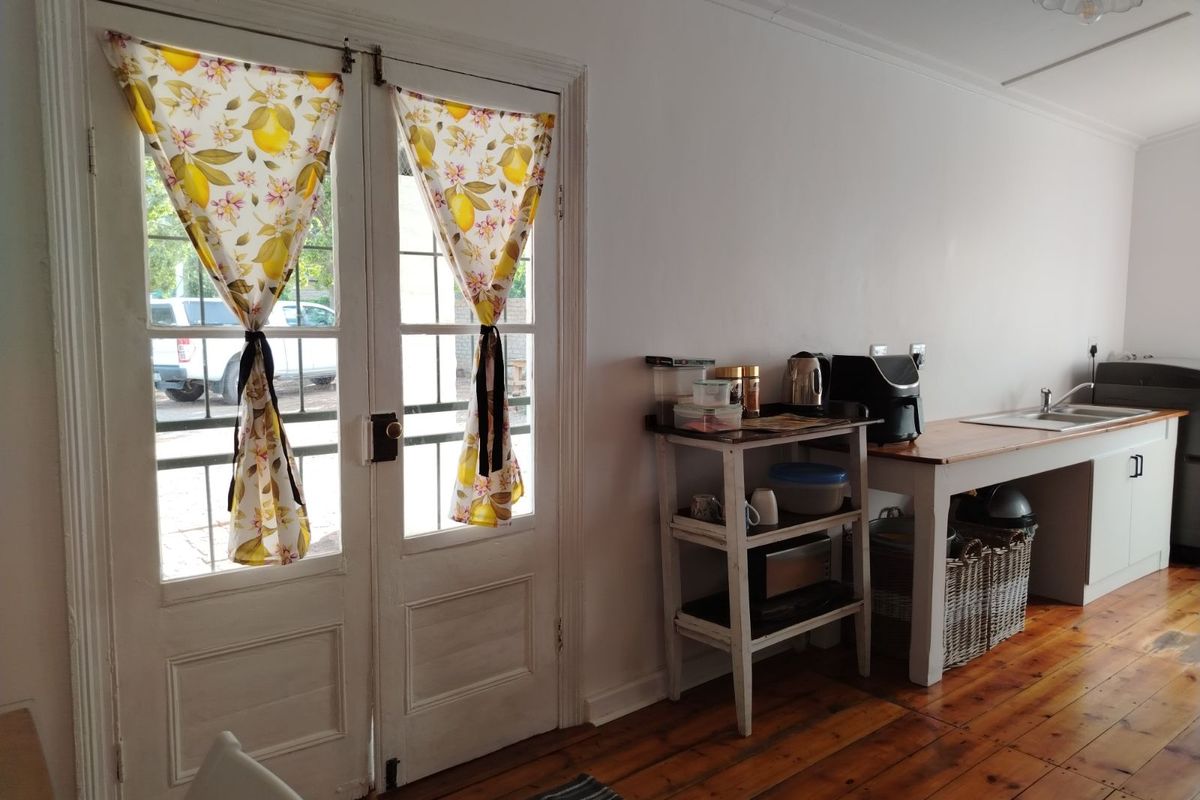A functional kitchen area featuring timber flooring, a built-in sink unit, and double glass-panelled doors providing direct access to the exterior.