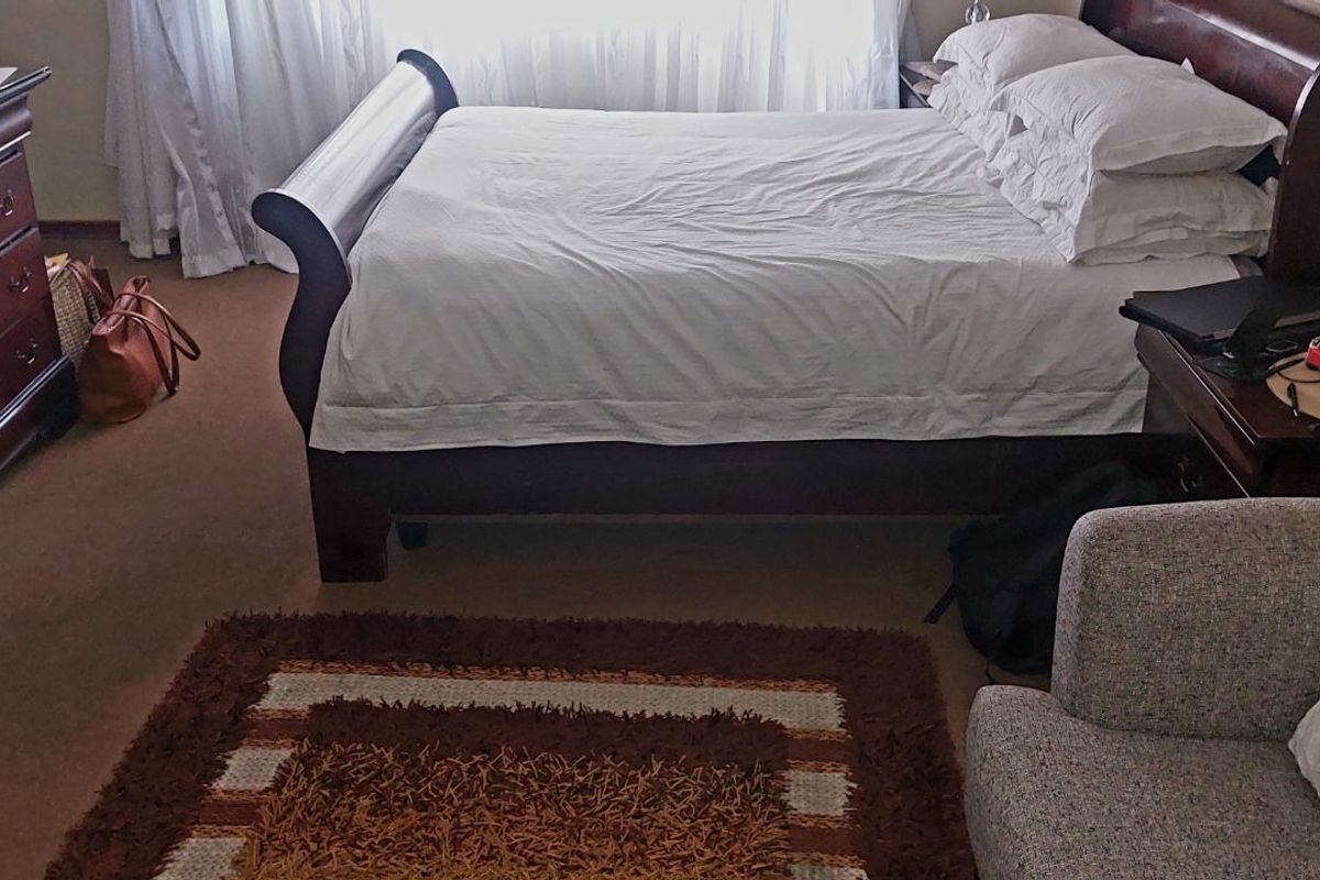 A carpeted bedroom featuring a window with curtains, providing a functional and comfortable living space.