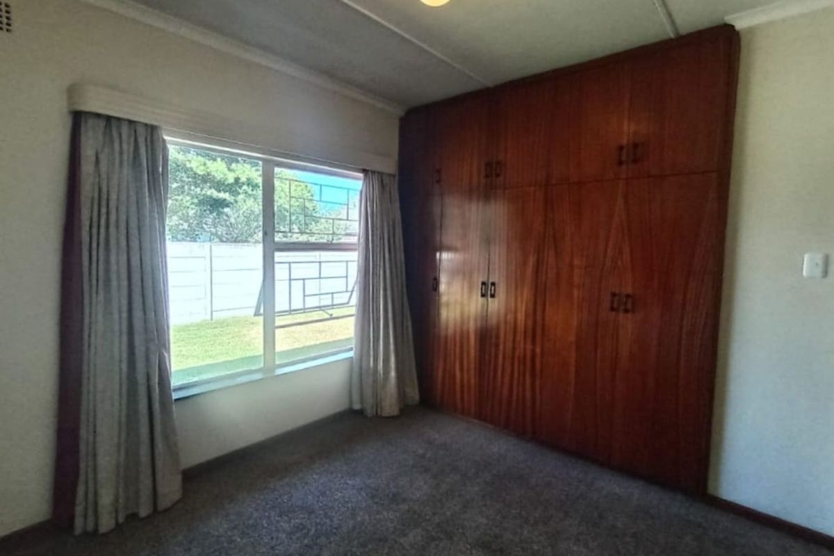 A bedroom featuring built-in wooden cabinetry and carpeted flooring, offering a functional space with natural light.