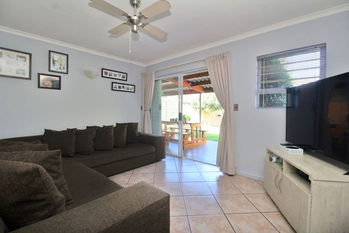A comfortable living room featuring tiled flooring, a ceiling fan, and sliding glass doors that provide direct access to the outdoor patio area.