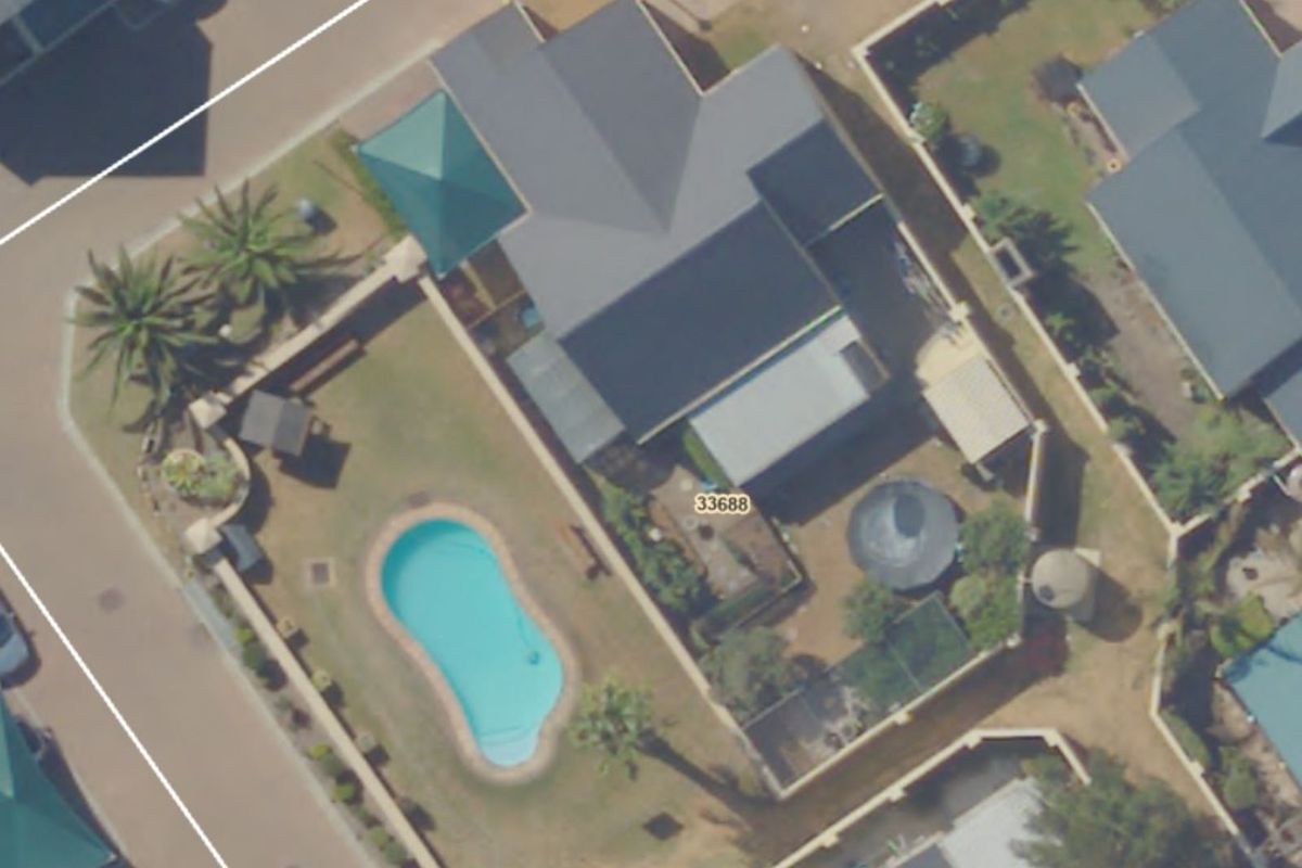 Aerial view of the property showing the house layout, swimming pool, garden area, and surrounding boundary walls.