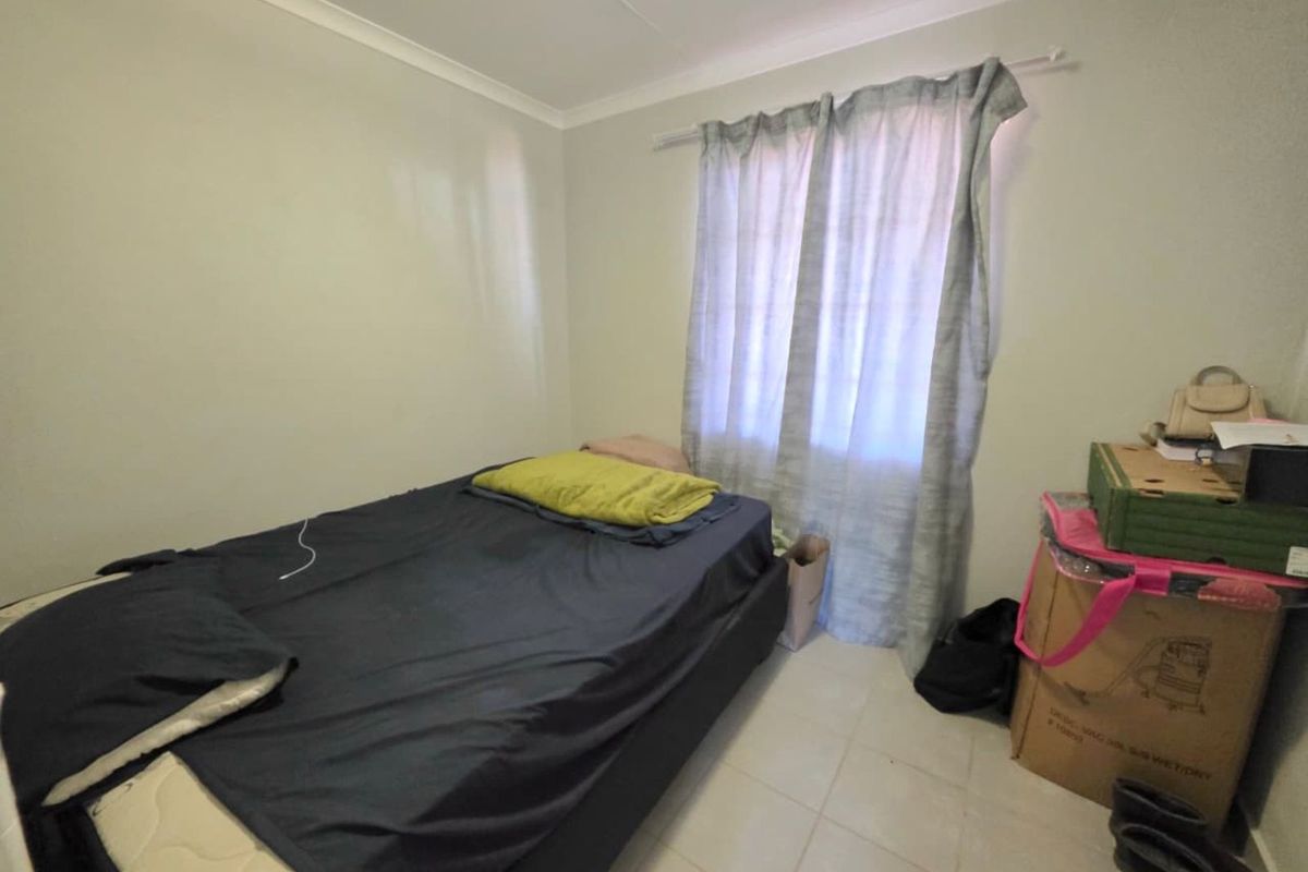 A standard bedroom featuring tiled flooring, neutral wall finishes, and a window with curtain track.