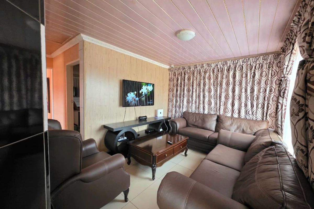 A living room featuring tiled flooring, wood-look wall paneling, and a tongue-and-groove ceiling finish.