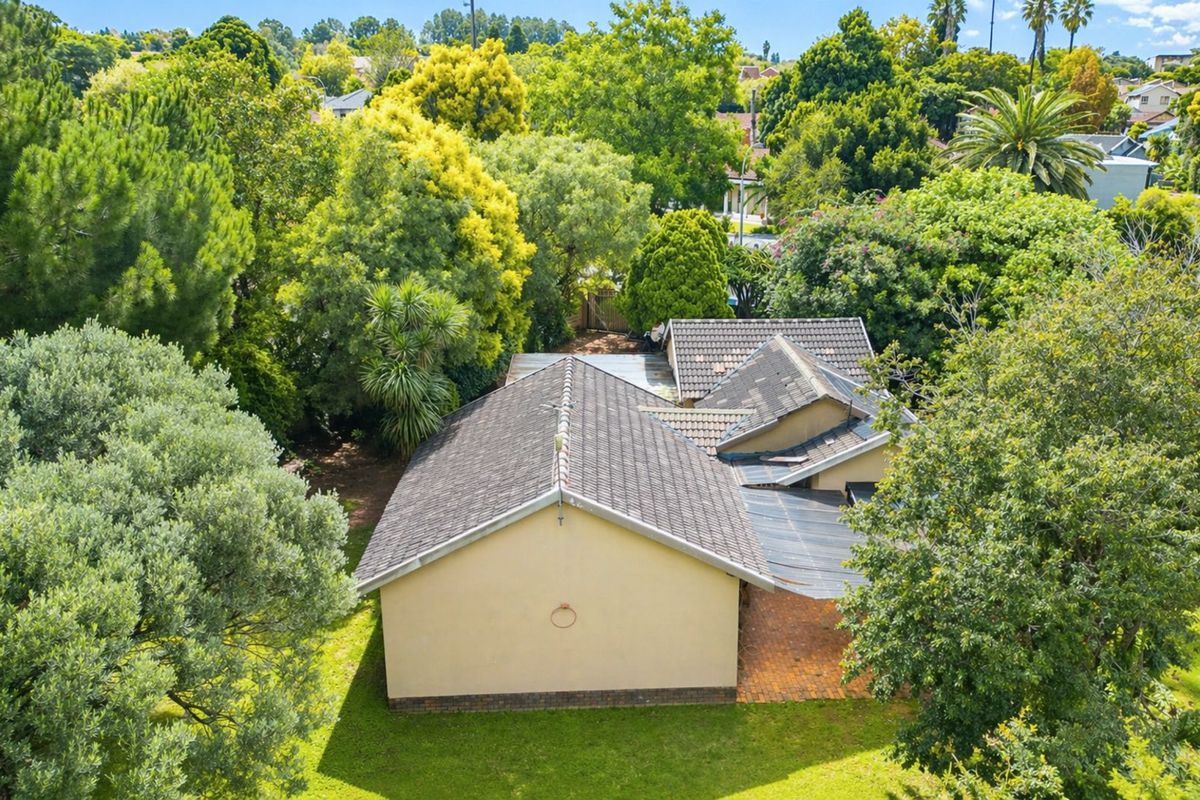 An aerial view of the property showing the tiled roof structure, rear garden area, and established surrounding trees.