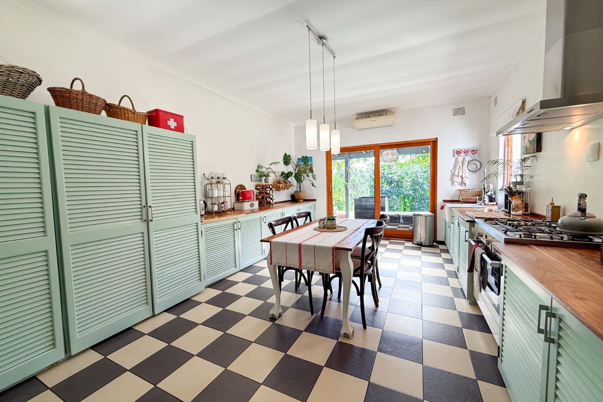 Spacious kitchen featuring light green cabinetry, wooden countertops, a gas hob, extractor fan, and checkered flooring with direct access to the rear garden.
