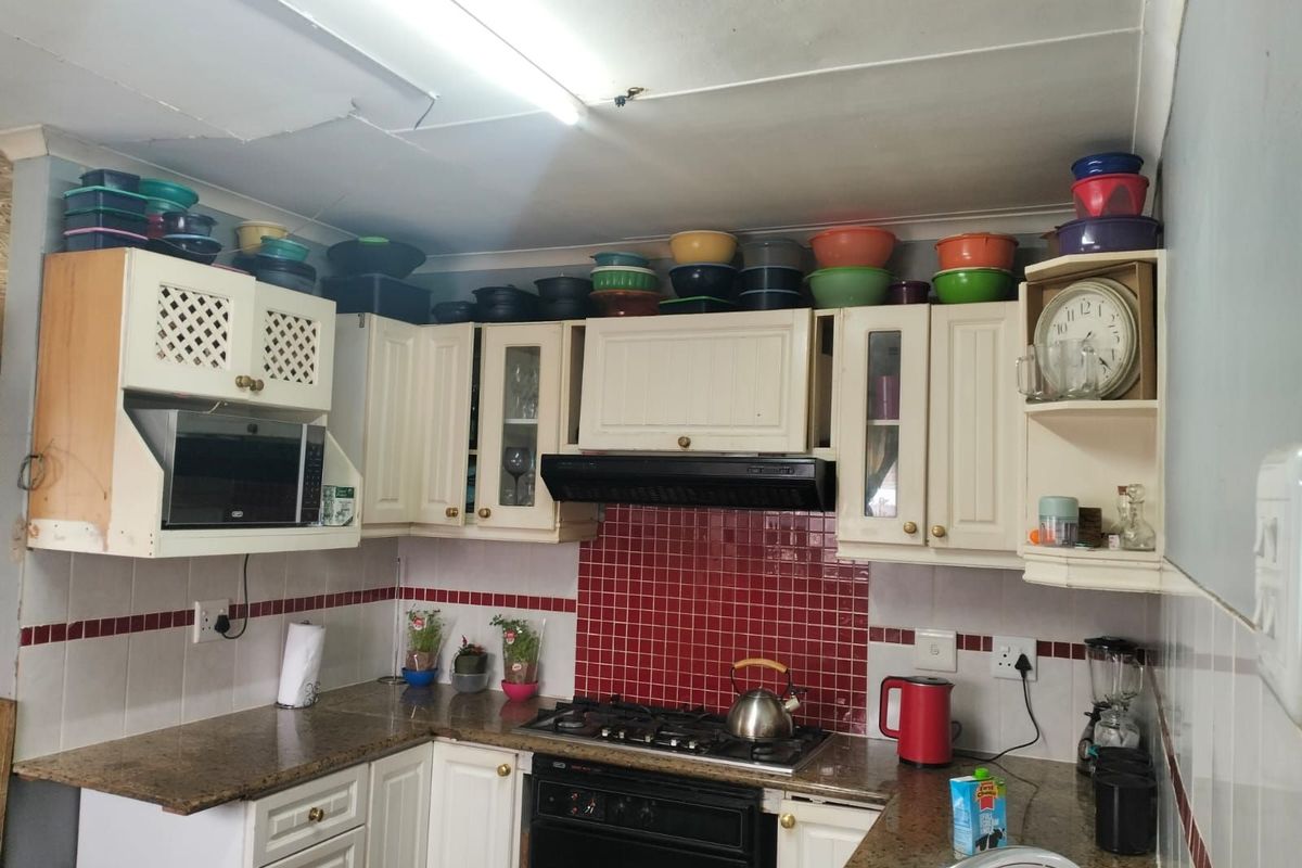 A functional kitchen featuring granite countertops, a gas hob, built-in oven, extractor fan, and tiled splashbacks with ample overhead cabinetry.