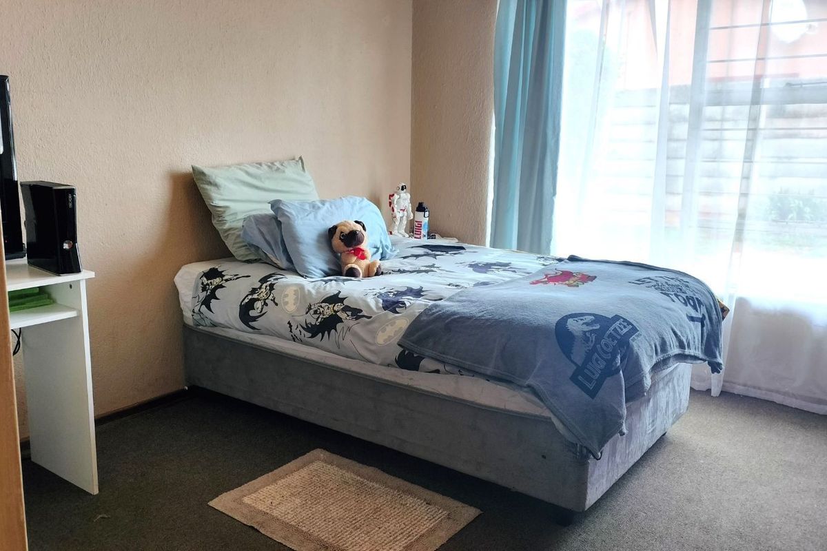 A standard bedroom featuring carpeted flooring and a large window with natural light.