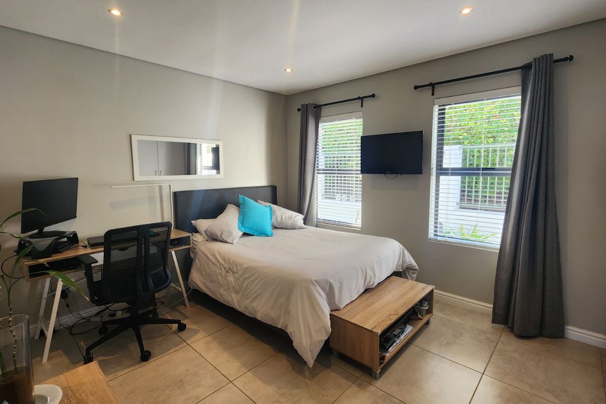 A well-maintained bedroom featuring tiled flooring, recessed ceiling lighting, and large windows with fitted blinds and curtain rods.