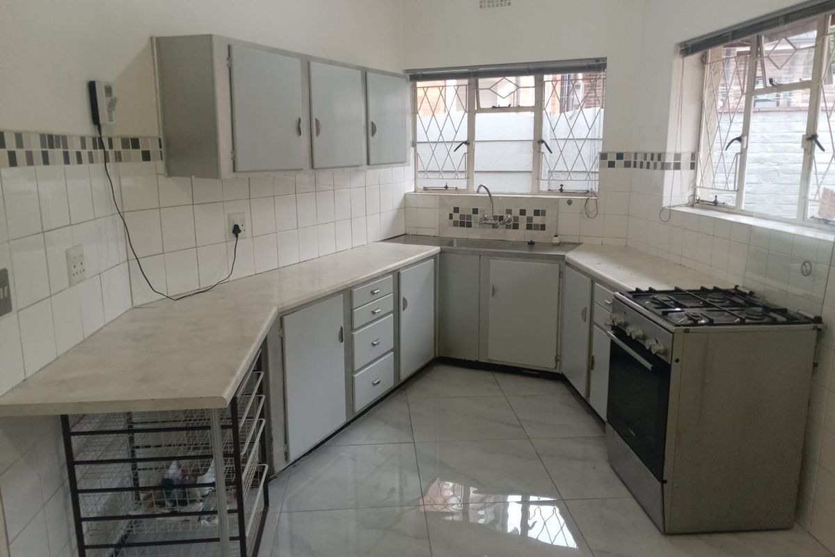 A functional kitchen featuring U-shaped cabinetry, tiled splashbacks, tiled flooring, and a freestanding gas stove with an integrated oven.