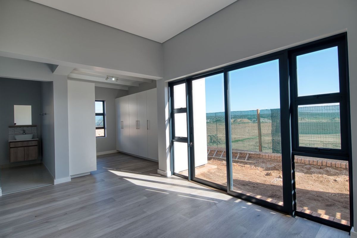 Modern bedroom featuring light wood-look flooring, built-in cabinetry, and large sliding glass doors opening to an outdoor area.