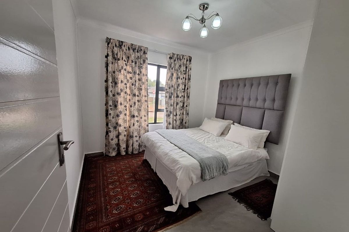 A well-maintained bedroom featuring tiled flooring, a modern light fixture, and a large window providing natural light.
