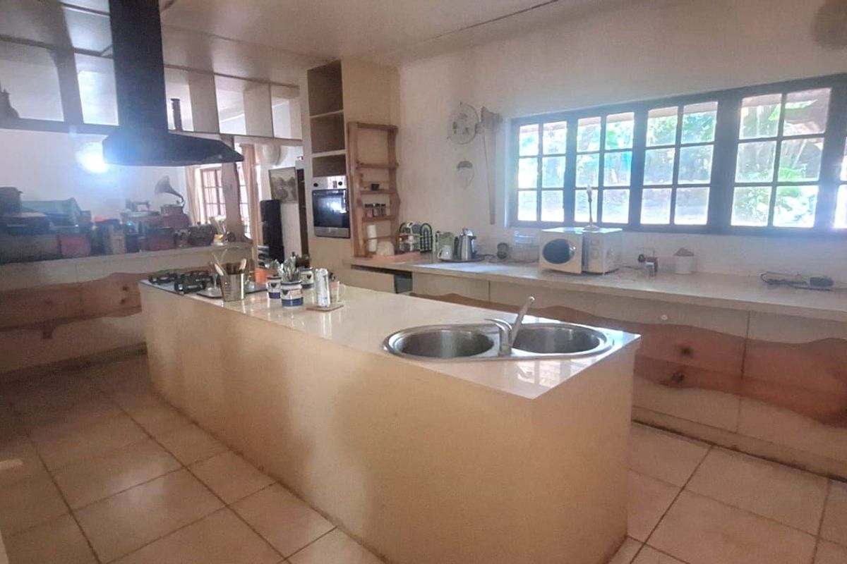 Spacious kitchen featuring a central island with a double sink, built-in oven, extractor fan, and extensive counter space with natural light.