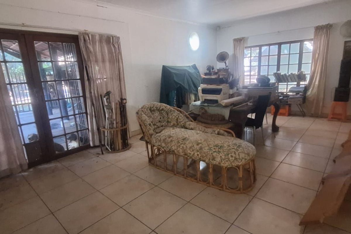 Spacious living area featuring tiled flooring, large wooden-framed glass doors leading to the patio, and ample natural light.
