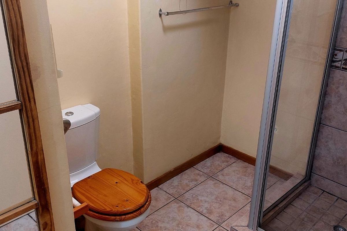 A functional bathroom featuring a tiled shower enclosure with glass door, a standard toilet, and a wall-mounted towel rail.