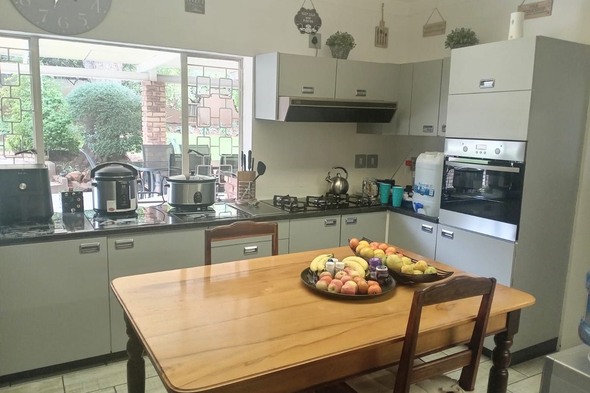 A functional kitchen featuring built-in cabinetry, a gas hob, an integrated oven, and an extractor fan, with a view overlooking the rear patio.
