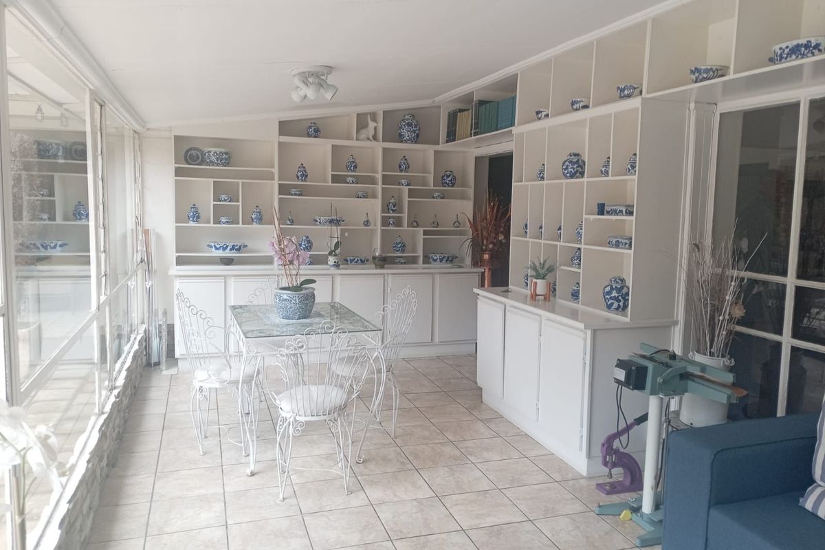 A sunroom featuring extensive built-in white shelving, tiled flooring, and large windows providing ample natural light.