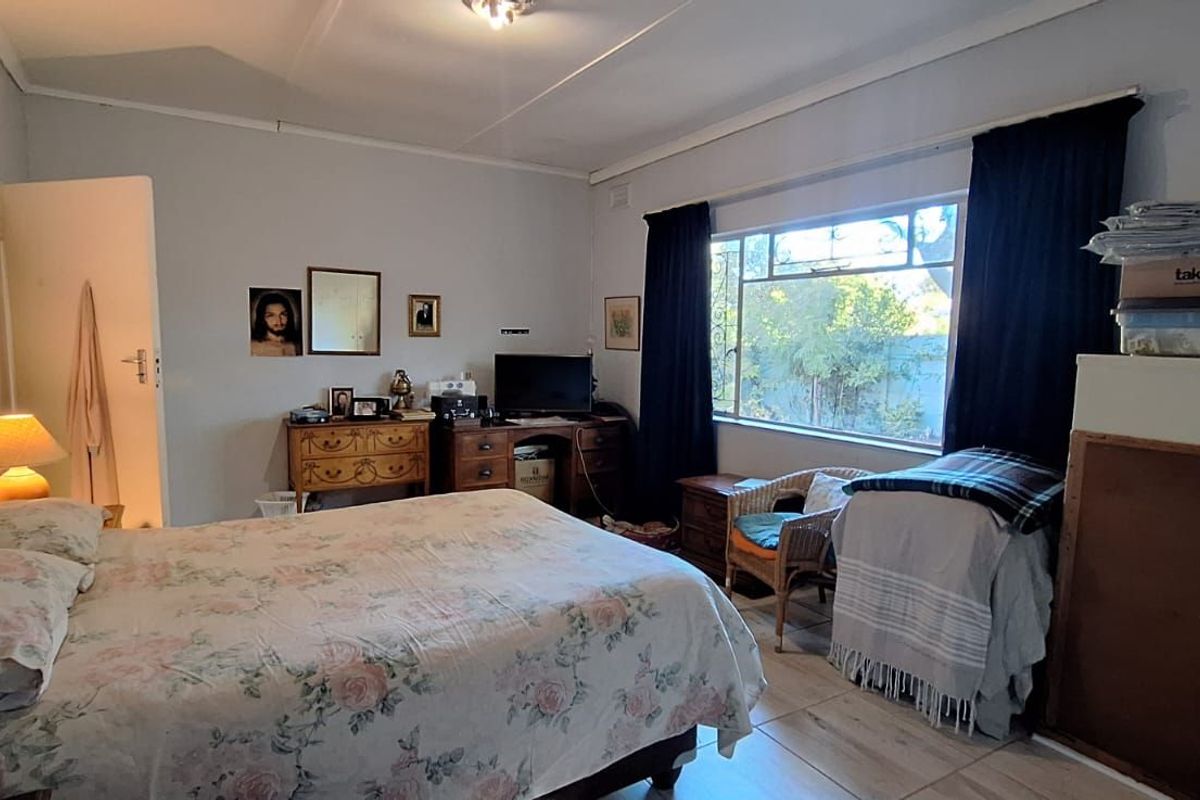 A spacious bedroom featuring large windows, tiled flooring, and neutral wall finishes, offering a comfortable and functional living space.