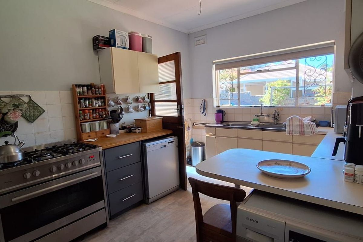 A functional kitchen featuring a gas stove, built-in cabinetry, double sink, and a breakfast nook area with natural light.