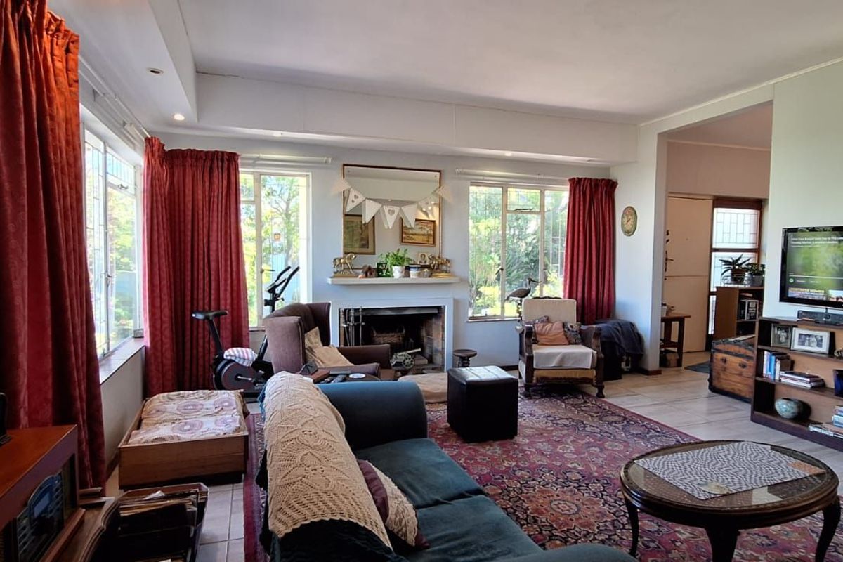 Spacious living room featuring a traditional fireplace, large windows allowing natural light, and tiled flooring, providing a comfortable and inviting family space.