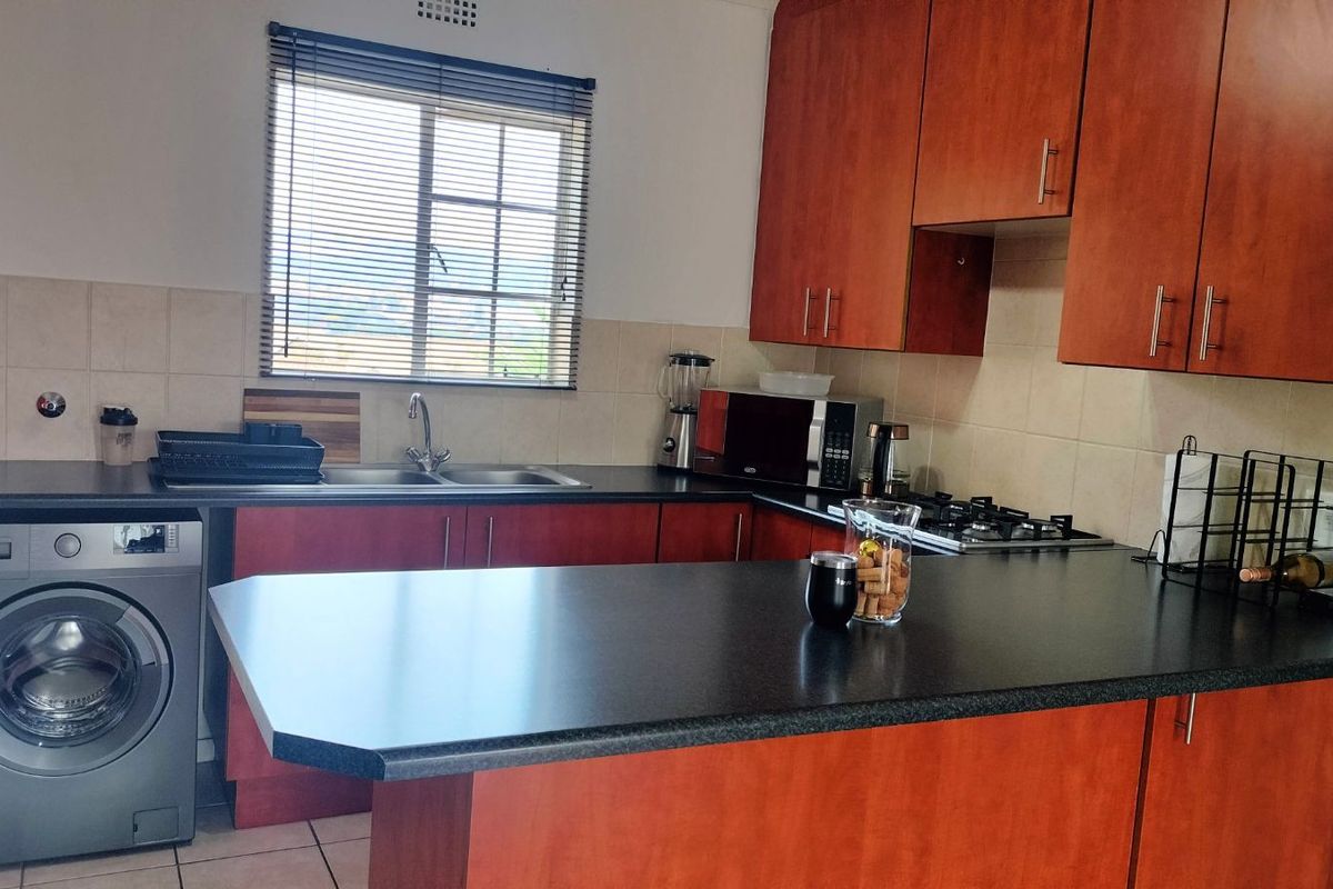 Functional kitchen featuring wood-tone cabinetry, dark laminate countertops, integrated gas hob, and a built-in washing machine connection.