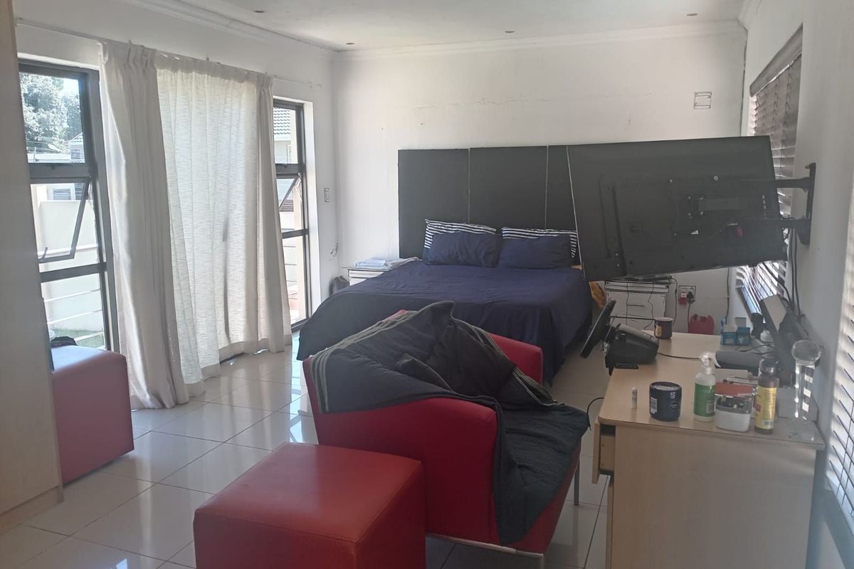 Spacious bedroom featuring large windows, tiled flooring, and a built-in headboard, offering ample natural light and a functional layout.