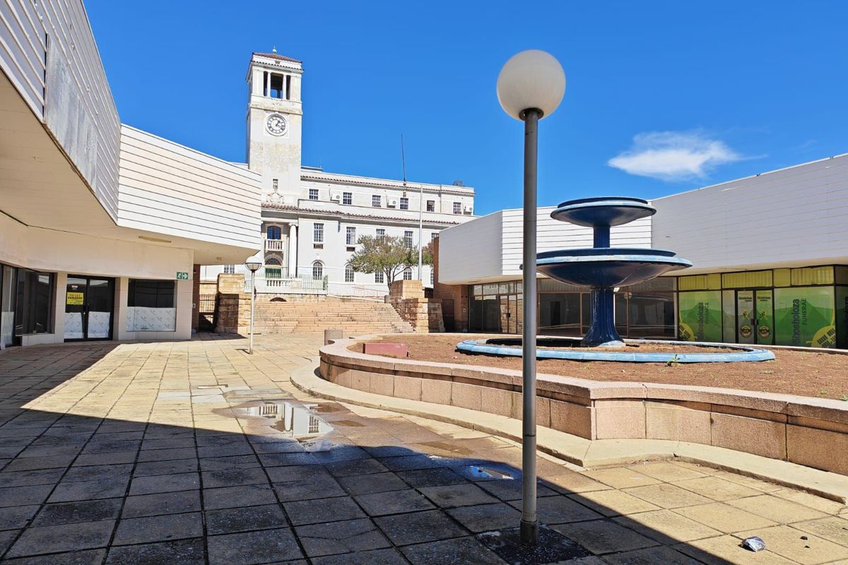 Exterior courtyard area featuring a central fountain, paved walkways, and views of a historic clock tower building.