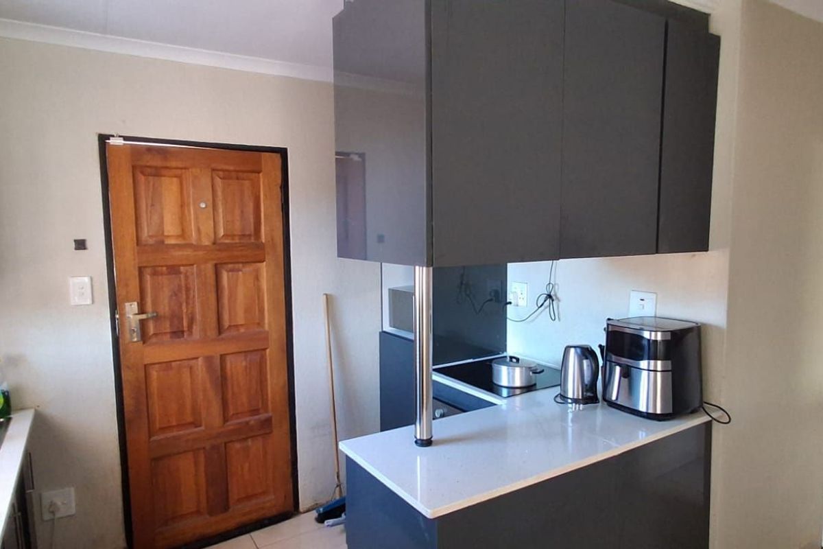A functional kitchen featuring modern dark grey cabinetry, stone countertops, and a built-in hob, providing a clean and efficient workspace.