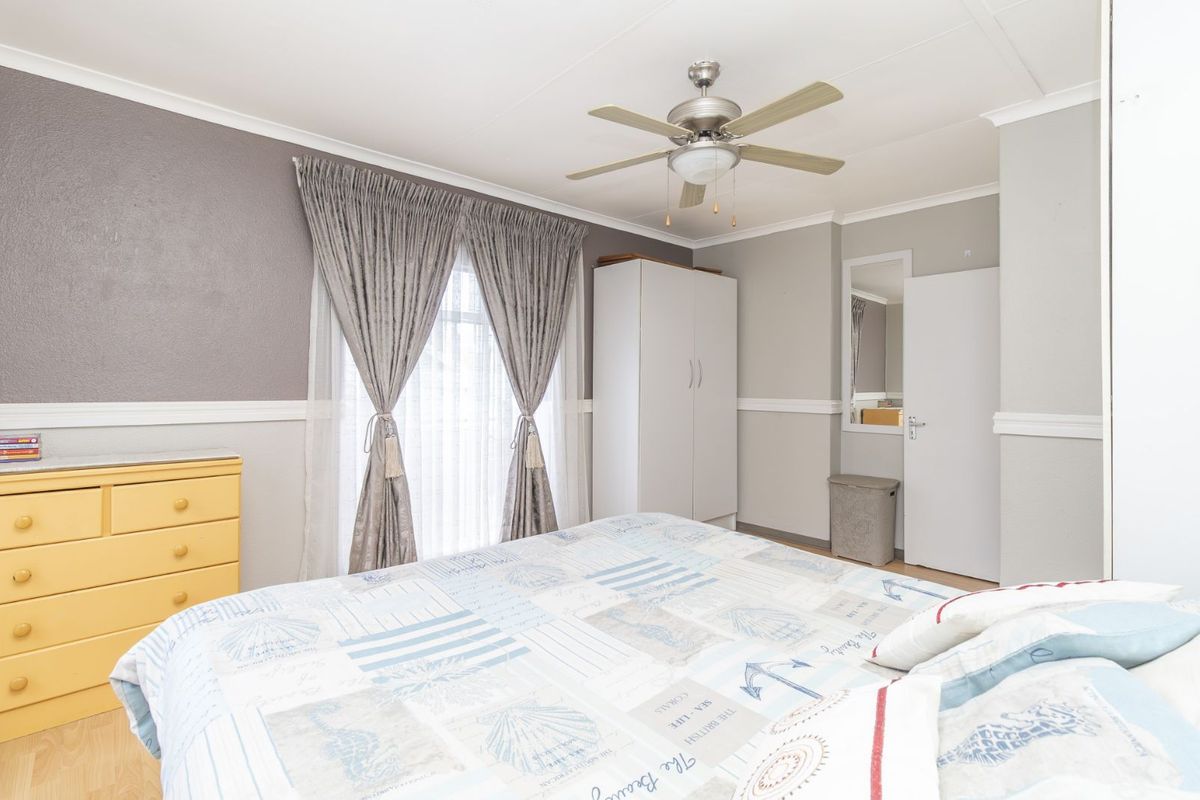 A bedroom featuring a ceiling fan, built-in wardrobe, and neutral wall finishes with a dado rail.