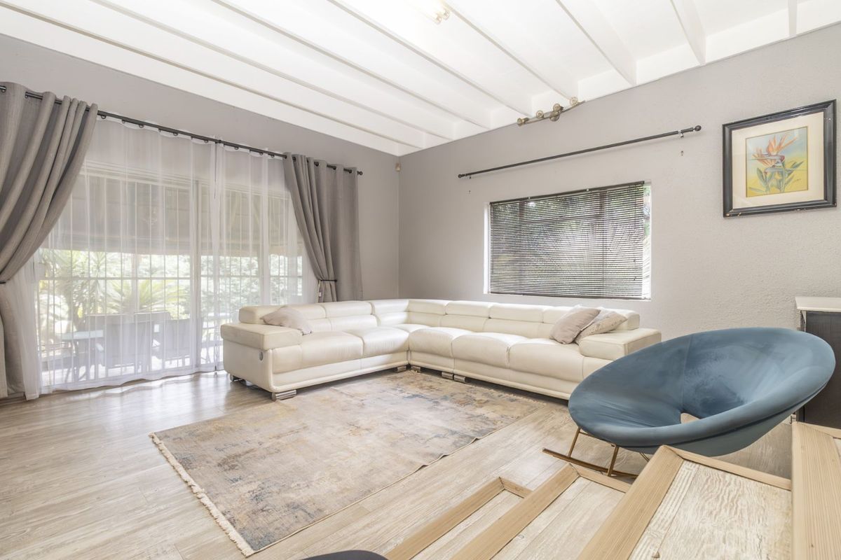 Spacious living room featuring exposed beam ceilings, large sliding glass doors leading to the patio, and wood-look flooring.