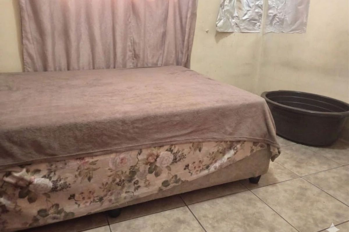 A bedroom featuring tiled flooring and a window with curtains.