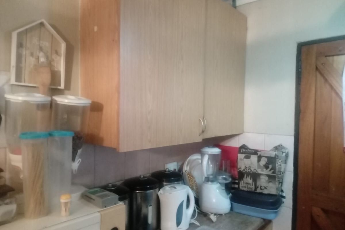 A compact kitchen area featuring light wood-tone wall-mounted cabinetry and a tiled splashback, providing functional storage and preparation space.