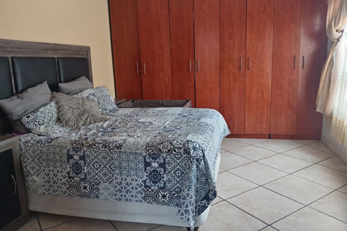A bedroom featuring large built-in wooden wardrobes and tiled flooring.