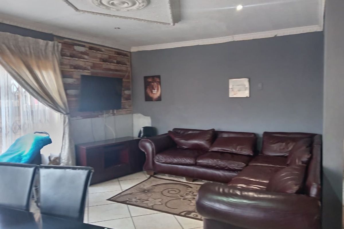 A living room featuring tiled flooring, decorative ceiling molding, and a feature wall with wood-look paneling.